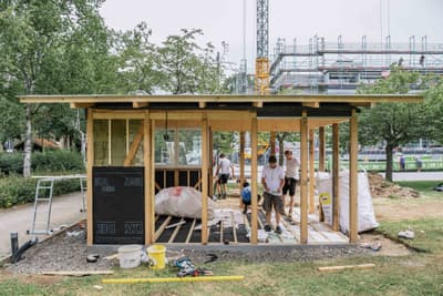 Architectural project - construction zone, collaborative work, new build, natural materials, wood, timber, temporary structure, scaffolding, urban setting, raw materials, outdoor space, timber frame, passive design, glass, natural tones, modular design, green building, innovative design, lightweight construction, sustainable architecture, construction site, construction workers, building assembly, outdoor construction, teamwork, urban development, building site, beige, timber facade, light wood, timber construction, prefab building, open framework, construction details, building process, wood structure, sustainable building, eco construction, timber walls, natural texture, eco-friendly building, green design, wooden facade, structural elements, architectural process, community project