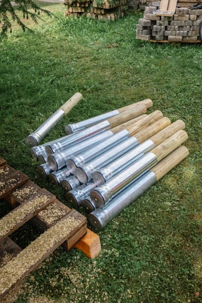 Architectural project - silver, construction elements, metal finish, nature backdrop, timber post, rustic materials, outdoor storage, material storage, lush environment, natural materials, sustainable materials, wood, timber, raw materials, steel, metal, natural tones, green, construction site, outdoor construction, construction materials, outdoor setting, beige, eco friendly, natural setting, building materials, site preparation, construction logistics, earthy tones, building components, green space, wood finish