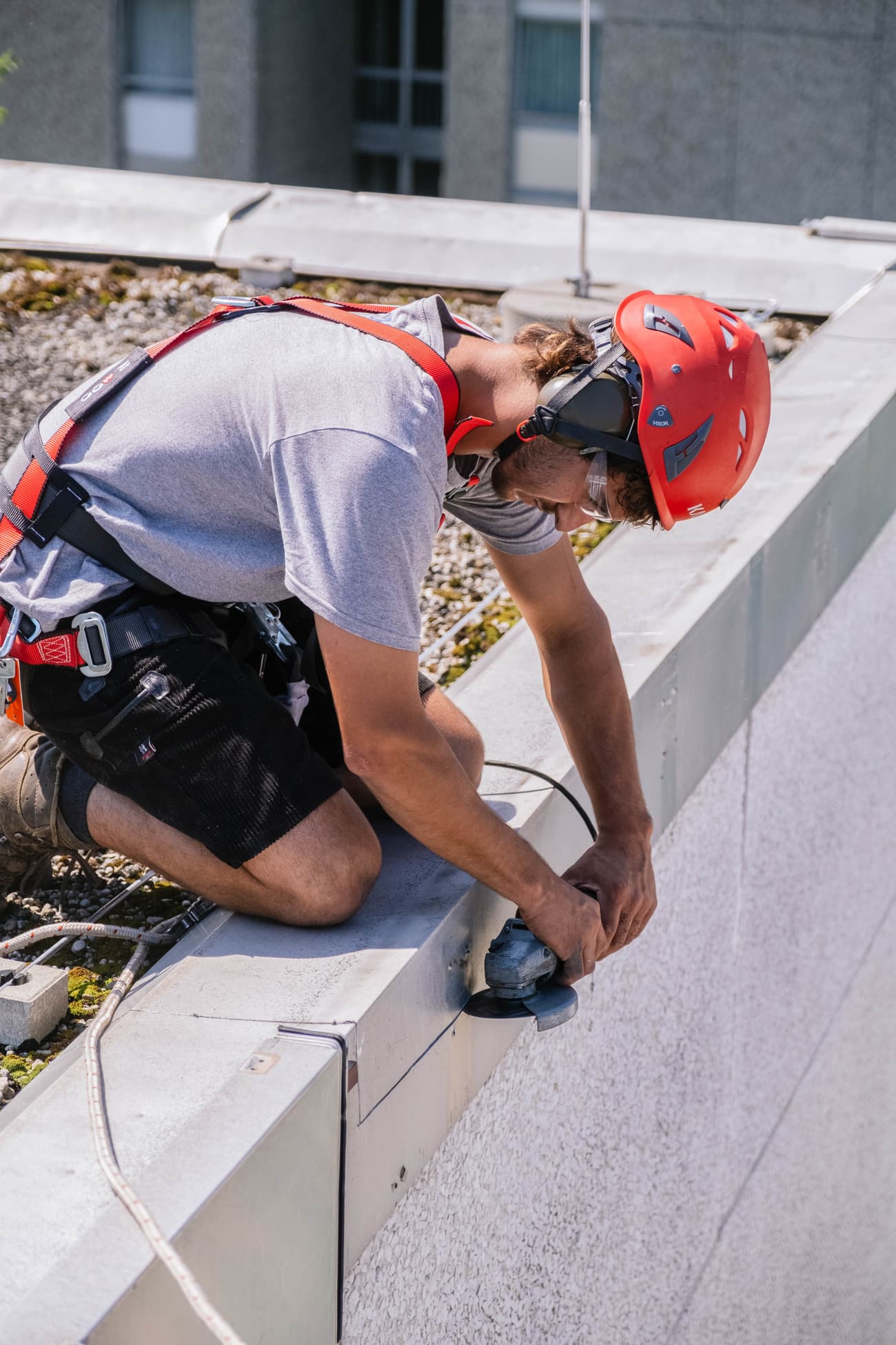 Architectural project - urban building, construction worker, outdoor work, workwear, commercial building, concrete building, rooftop, building repair, power tools, cityscape, construction site, safety gear, modern construction, urban environment, construction process, construction project, city building, exterior wall, urban architecture