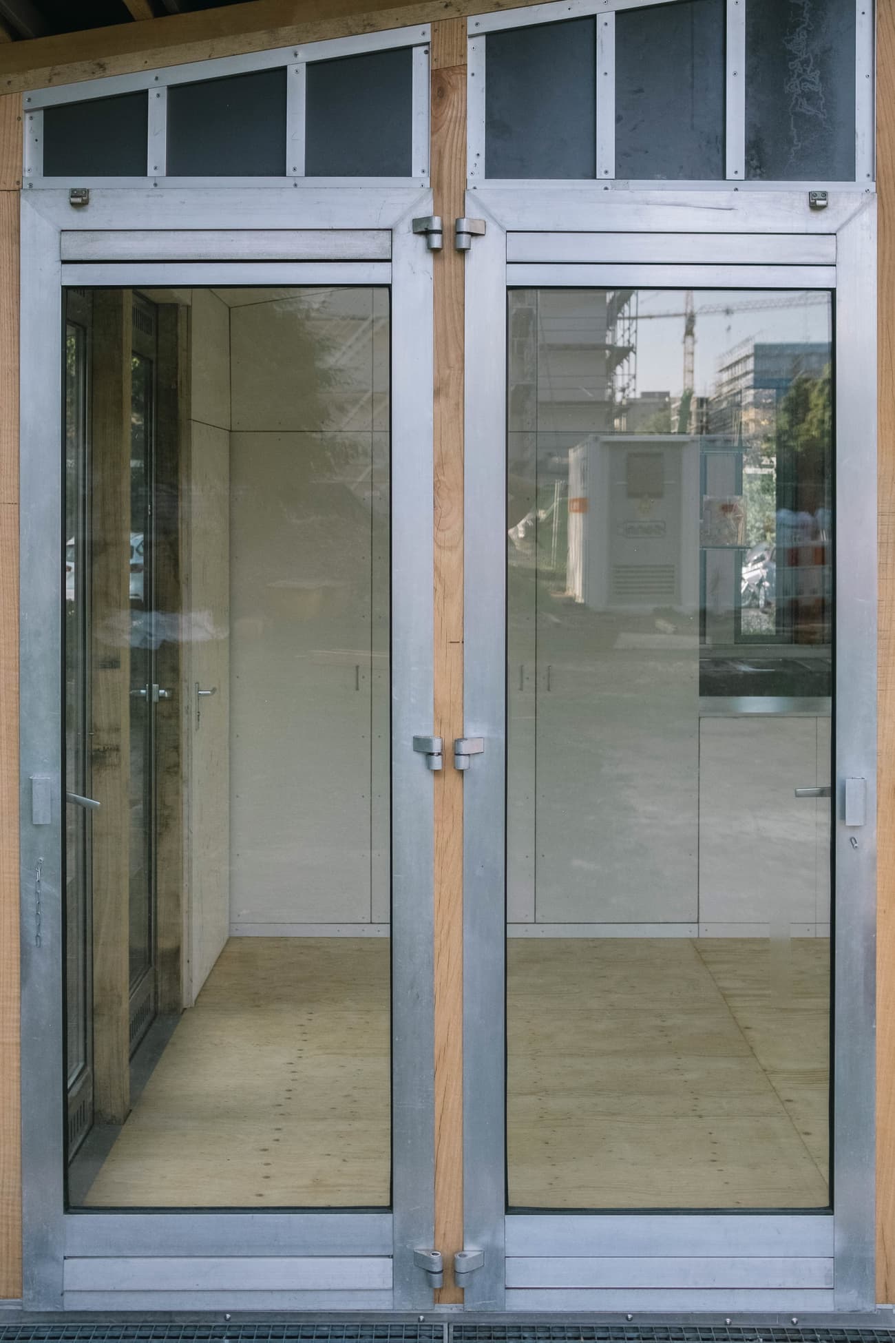 Architectural project - urban building, private space, double doors, eco-friendly design, sustainable materials, urban setting, metal frame, timber frame, natural light, neutral tones, urban environment, city architecture, light wood, industrial style, functional design, exterior detail, contemporary design, sleek lines, minimalist design, glass doors, open facade, steel frame, urban space, urban design, architecture detail, clean lines, energy efficient, wood accents, exterior view, reflective surface, minimalist aesthetic, urban architecture, glass facade, glass wall, street view, modern materials, modern entry