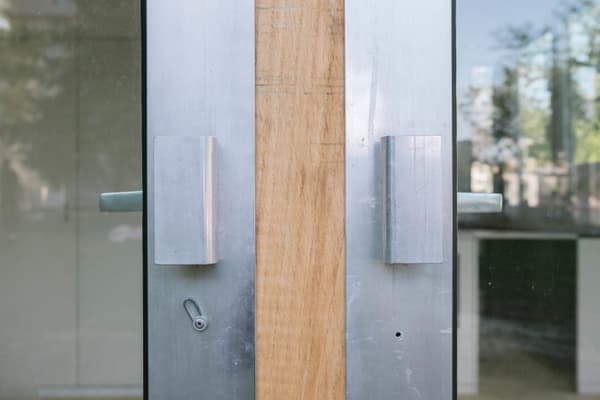 Architectural project - silver, metal finish, contemporary door, architectural detail, wood, timber, steel, metal, sustainable design, glass, grey, neutral tones, city architecture, beige, timber detail, light wood, functional design, exterior detail, minimalist vibe, industrial touch, minimalist design, urban design, clean aesthetic, eco-friendly materials, geometric design, natural material, modern facade, clean lines, modern architecture, reflective surface, sleek design, glass door, aluminum, glass facade, metal handle, urban facade, modern entry