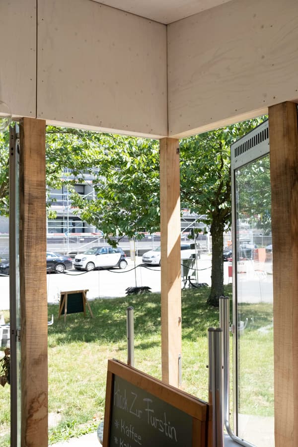 Architectural project - urban greenery, exposed timber, glazed facade, casual vibe, urban cafe, transparent facade, gathering spot, transparent, open entrance, natural materials, wood, timber, urban setting, cityscape, wooden frame, natural light, sustainable design, glass, eco design, community space, green, timber structure, daylight, light wood, eco friendly, natural setting, sunlight, rustic charm, light brown, minimalist design, relaxed atmosphere, outdoor seating, glass doors, raw wood, earth tones, biophilic design, indoor outdoor, outdoor view, inviting entrance, nature integration, open air, bright space, green surroundings, airy feel, wood paneling, street view
