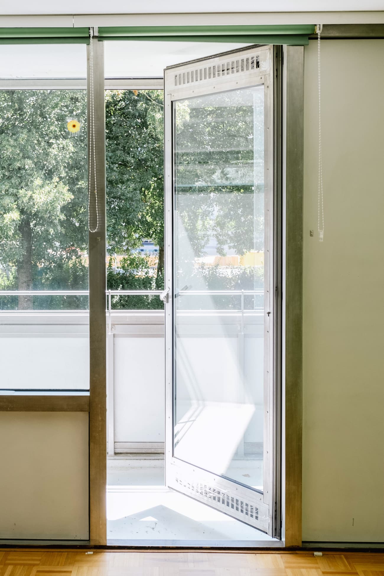 Architectural project - balcony, airy interior, open door, green view, light wood floor, fresh atmosphere, minimalist, wood, metal frame, city living, metal, natural light, sustainable design, glass, contemporary style, green, daylight, beige, eco friendly, modern design, simple design, clean lines, white walls, indoor outdoor, white, large window, cozy corner, residential space, glass door, home design, seamless transition, glass facade, sliding door, connection to nature, calming vibe, spacious feel, bright room, urban apartment