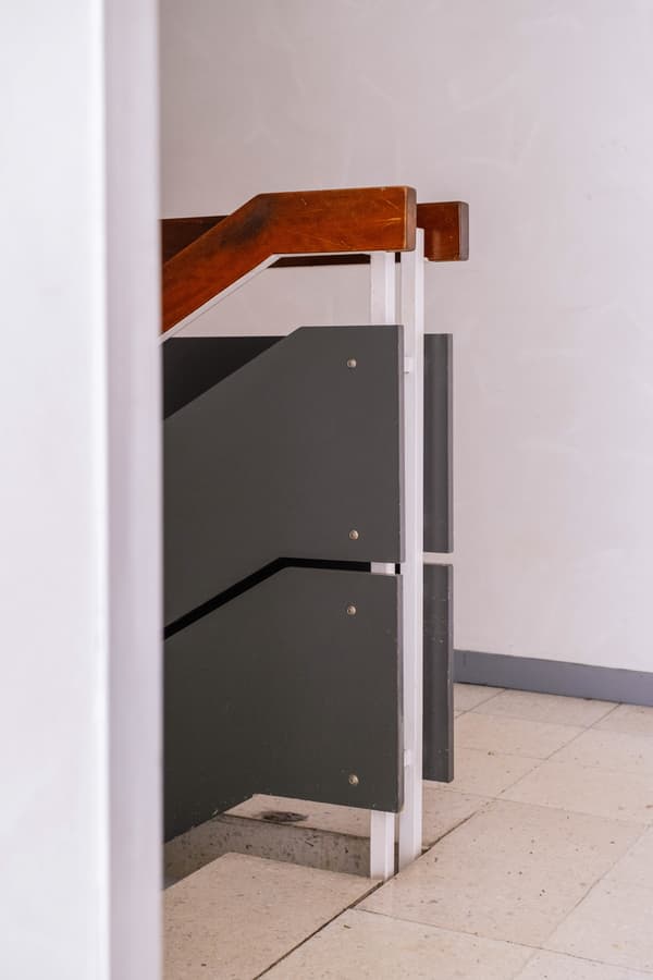 Architectural project - metal railing, minimalist stairs, modern staircase, contrasting materials, beige floor, understated style, smooth surface, white wall, subtle detail, light floor, architectural detail, grey tones, neutral tones, functional space, modern aesthetic, simple design, minimalist vibe, industrial touch, contemporary interior, minimalist design, geometric design, clean lines, textured wall, stone floor, sleek design, practical design, staircase, home stairs, mixed materials, residential interior, indoor staircase, wood finish