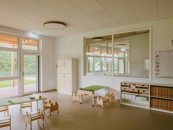 Architectural project - glass partition, beige floor, spacious room, educational environment, creativity space, natural materials, eco-friendly design, natural light, inviting atmosphere, warm tones, honey wood, contemporary design, neutral palette, minimalist design, cozy space, clean lines, white walls, large windows, indoor outdoor connection, child friendly, bright interior, functional layout, simple decor, educational space, playroom, sustainable interior, learning environment, calm setting, play area