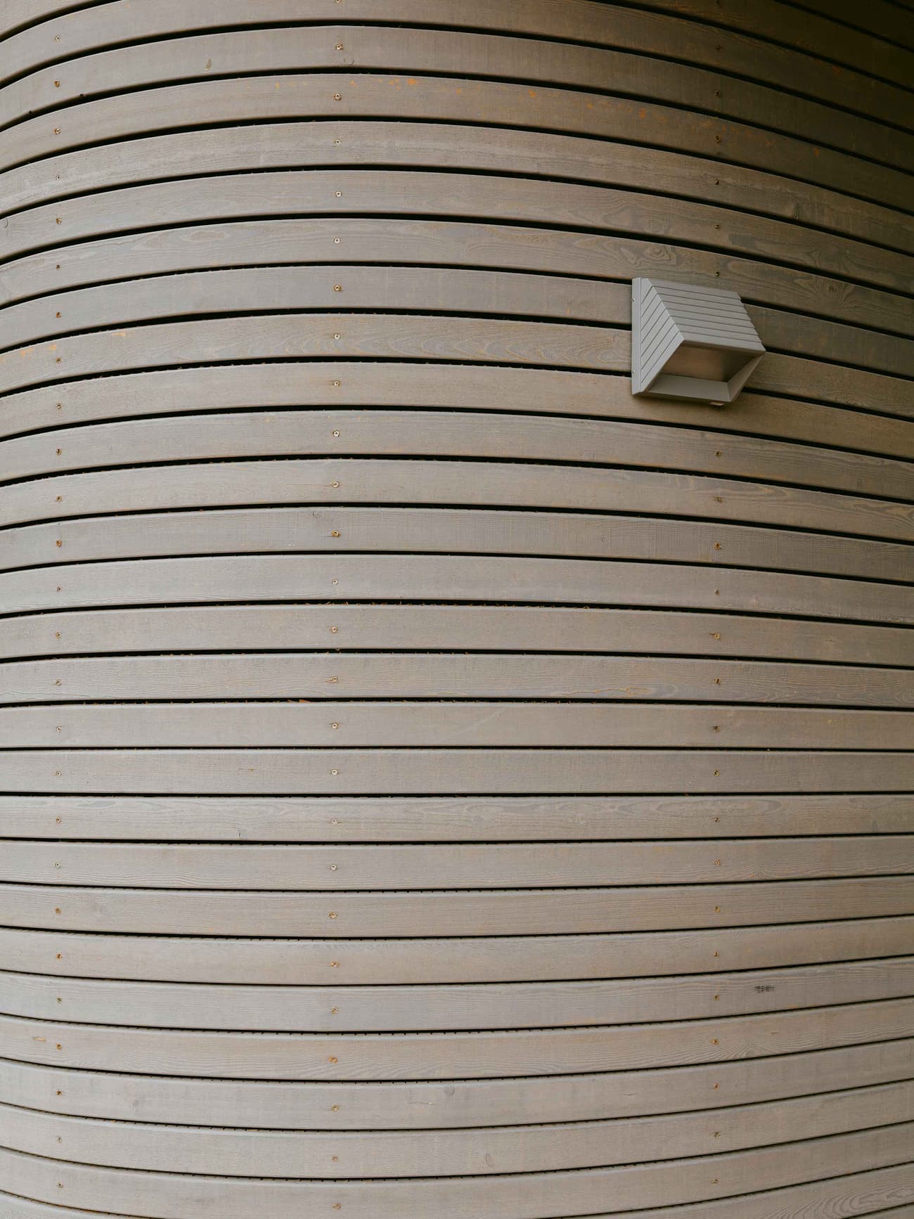 Architectural project - light grey, exterior architecture, timber texture, timber slats, curved facade, minimalist lighting, natural materials, architectural detail, wood, timber, sustainable design, eco design, sustainable architecture, neutral tones, timber facade, eco friendly, exterior detail, organic design, architectural lighting, contemporary design, timber building, timber architecture, clean lines, timber cladding, wood cladding, modern architecture, wooden architecture, wood slats, wooden facade, minimalist exterior, wooden texture, sleek design, innovative facade, curved wall, wood architecture, modern exterior, curved design, building envelope, timber finish, wood finish
