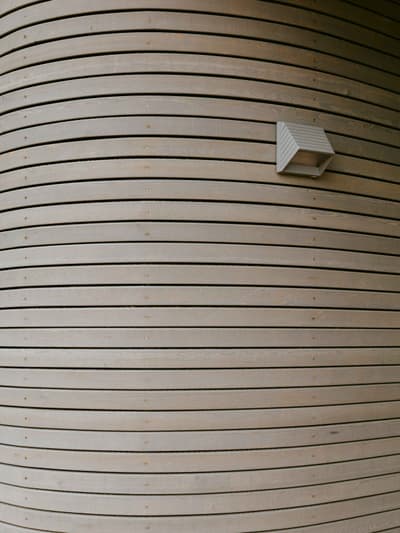 Architectural project - light grey, exterior architecture, timber texture, timber slats, curved facade, minimalist lighting, natural materials, architectural detail, wood, timber, sustainable design, eco design, sustainable architecture, neutral tones, timber facade, eco friendly, exterior detail, organic design, architectural lighting, contemporary design, timber building, timber architecture, clean lines, timber cladding, wood cladding, modern architecture, wooden architecture, wood slats, wooden facade, minimalist exterior, wooden texture, sleek design, innovative facade, curved wall, wood architecture, modern exterior, curved design, building envelope, timber finish, wood finish