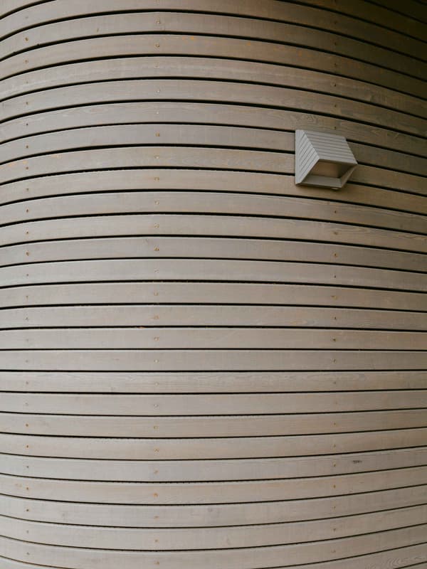 Architectural project - light grey, exterior architecture, timber texture, timber slats, curved facade, minimalist lighting, natural materials, architectural detail, wood, timber, sustainable design, eco design, sustainable architecture, neutral tones, timber facade, eco friendly, exterior detail, organic design, architectural lighting, contemporary design, timber building, timber architecture, clean lines, timber cladding, wood cladding, modern architecture, wooden architecture, wood slats, wooden facade, minimalist exterior, wooden texture, sleek design, innovative facade, curved wall, wood architecture, modern exterior, curved design, building envelope, timber finish, wood finish