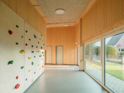 Architectural project - indoor play, spacious room, vibrant environment, minimal design, cozy interior, natural materials, eco-friendly design, sustainable materials, wood, timber, natural light, pastel colors, modular design, community space, grey, neutral tones, daylight, beige, light wood, honey wood, Scandinavian style, recreation area, glass doors, timber panels, wood panels, clean lines, Nordic design, timber interior, warm atmosphere, playful vibe, multifunctional room, bright interior, sliding doors, open space, educational space, playful space, learning environment, family-friendly, wood interior