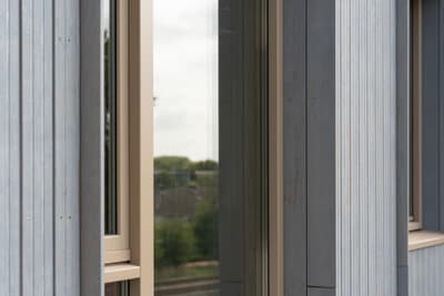 Architectural project - facade, modern building, vertical lines, glazed facade, metal cladding, light grey, architectural detail, grey tones, natural light, passive design, eco design, grey, beige, exterior design, building facade, minimalist facade, light wood, daylight optimization, exterior detail, contemporary design, industrial touch, neutral palette, minimalist design, light tones, modern facade, corrugated metal, clean lines, large windows, energy efficient design, modern architecture, outdoor view, residential building, sustainable facade, textured facade, sleek design, urban architecture, modern exterior, vertical panels, window detail, building envelope, exterior cladding, urban living