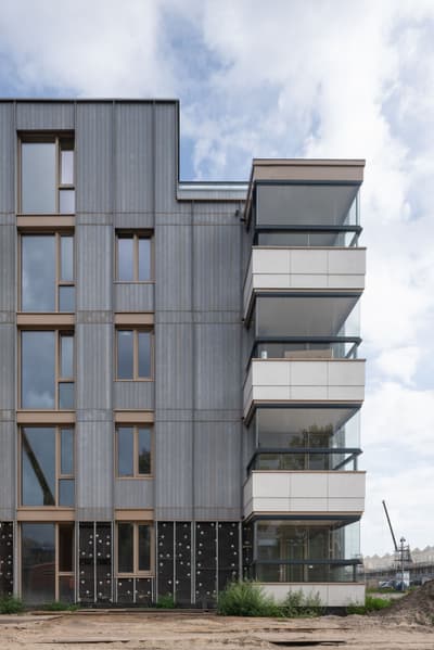 Architectural project - multi-story building, vertical lines, gray, metal cladding, cladding, minimalistic look, minimal design, natural materials, wood, city living, grey tones, metal, outdoor space, glass, modular construction, eco design, green building, sustainable architecture, urban development, beige, concrete, low carbon design, daylight optimization, contemporary design, neutral palette, passive house, modern facade, clean lines, energy efficient, timber accents, environmental design, residential building, balcony design, sustainable facade, cutting-edge design, building envelope, apartment building, modern urban, urban facade, urban living, architectural innovation