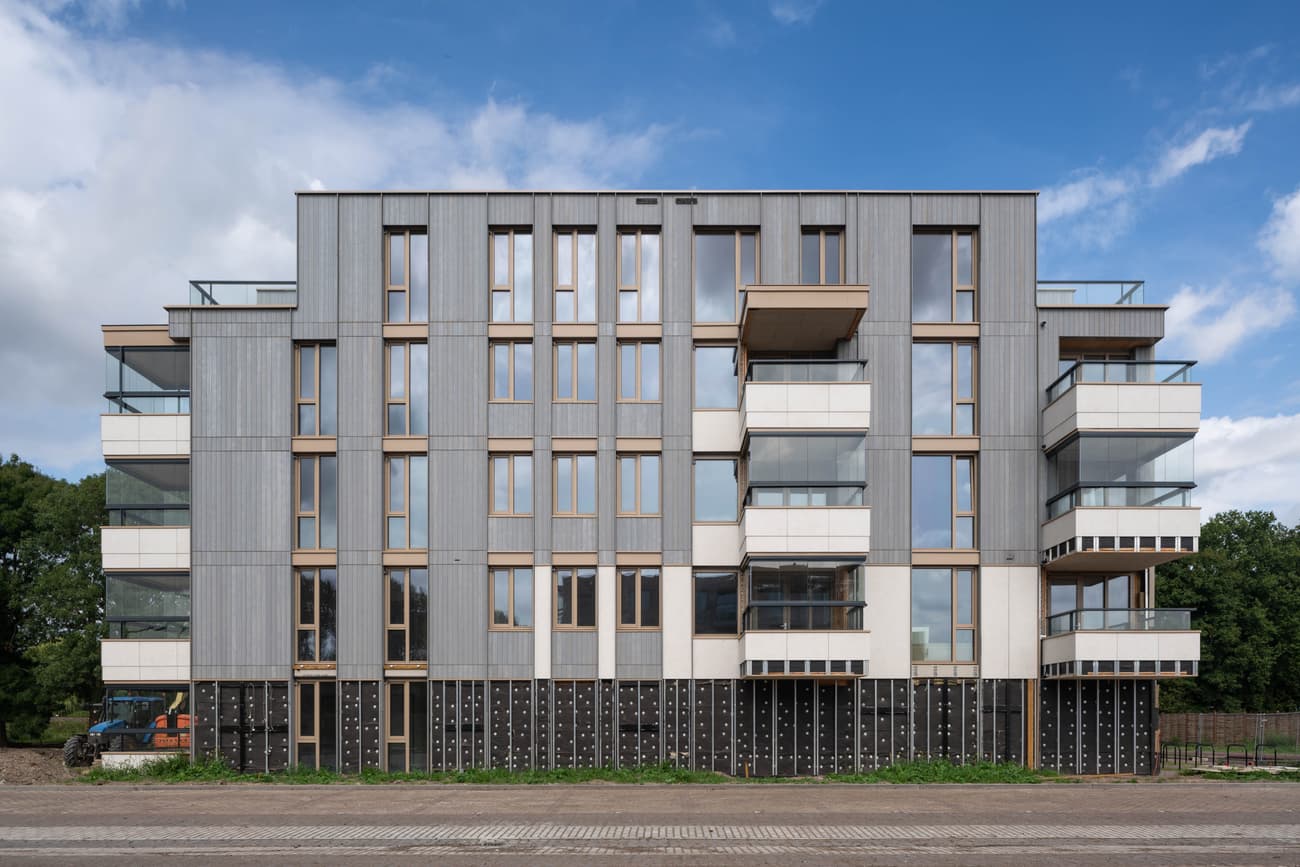 Architectural project - multi-story building, vertical lines, floor to ceiling windows, silver, metal facade, aluminum cladding, light grey, cubic form, multi-family housing, city living, warm tones, natural tones, modular design, contemporary architecture, urban landscape, urban development, beige, exterior design, minimalist design, eco-friendly materials, geometric design, modern aesthetics, passive house, natural ventilation, modern facade, clean lines, large windows, timber cladding, outdoor view, energy efficient, wood accents, eco architecture, sleek design, compact living, facade design, architectural rhythm, sustainable living, apartment building, residential block, stylish exterior, urban living