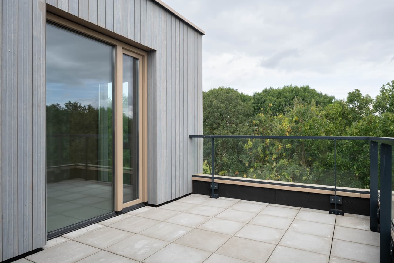 Architectural project - rooftop garden, tile, grey tiles, rooftop terrace, light gray, glass railing, natural materials, eco-friendly design, wood, glass, contemporary architecture, grey, green, neutral tones, minimalist style, modern facade, scenic view, green landscape, large windows, timber cladding, wood cladding, garden view, nature integration, modern home, sleek design, outdoor deck, sliding doors, open space, airy atmosphere, vertical panels, sustainable living, outdoor relaxation, urban retreat
