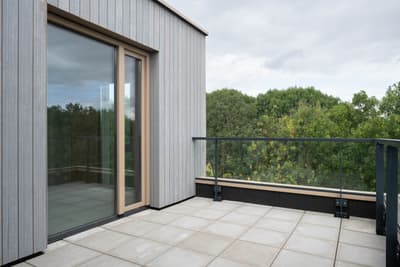 Architectural project - rooftop garden, tile, grey tiles, rooftop terrace, light gray, glass railing, natural materials, eco-friendly design, wood, glass, contemporary architecture, grey, green, neutral tones, minimalist style, modern facade, scenic view, green landscape, large windows, timber cladding, wood cladding, garden view, nature integration, modern home, sleek design, outdoor deck, sliding doors, open space, airy atmosphere, vertical panels, sustainable living, outdoor relaxation, urban retreat