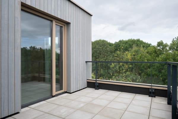 Architectural project - rooftop garden, tile, grey tiles, rooftop terrace, light gray, glass railing, natural materials, eco-friendly design, wood, glass, contemporary architecture, grey, green, neutral tones, minimalist style, modern facade, scenic view, green landscape, large windows, timber cladding, wood cladding, garden view, nature integration, modern home, sleek design, outdoor deck, sliding doors, open space, airy atmosphere, vertical panels, sustainable living, outdoor relaxation, urban retreat