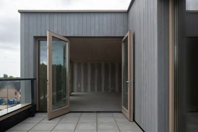 Architectural project - urban dwelling, light grey, muted colors, balcony access, open doors, city view, natural materials, wood, timber, grey tones, outdoor space, passive design, sustainable design, glass, contemporary style, grey, exterior design, light wood, functional design, flat roof, minimalist vibe, minimalist architecture, neutral palette, glass doors, eco home, modern facade, clean lines, timber cladding, architectural details, simple forms, wooden facade, residential building, modern home, sleek design, vertical cladding, energy efficiency, terrace access, urban facade, urban living