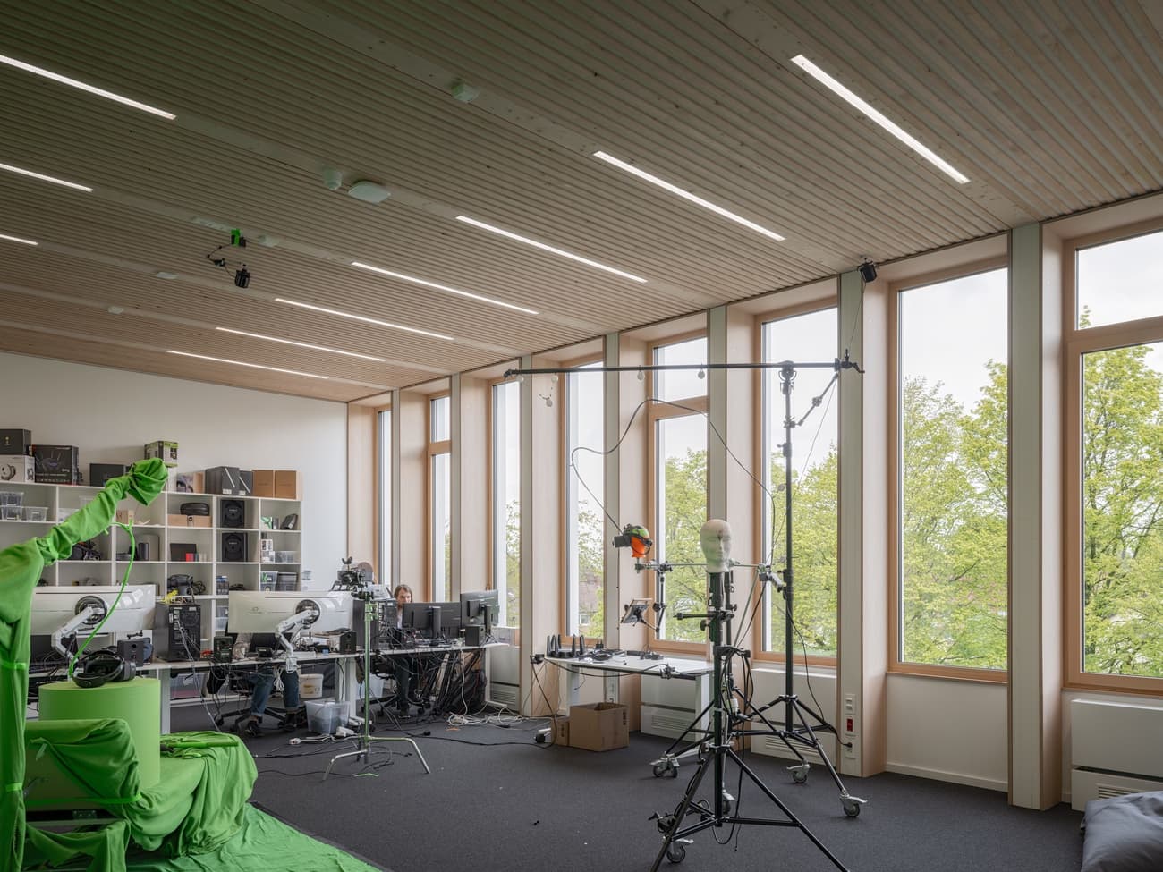 Architectural project - multitasking space, creative studio, ergonomic design, relaxing environment, modern office, collaborative area, office studio, open workspace, workstation, office equipment, tech setup, ceiling slats, grey carpet, acoustic panels, tech-friendly, computer setup, inspiring workspace, matte finish, minimal design, wood, timber, grey tones, natural light, sustainable design, glass, eco design, green building, neutral tones, daylight, light wood, modern aesthetic, honey wood, Scandinavian style, workspace, biophilic design, passive house, natural ventilation, large windows, Nordic design, outdoor view, energy efficient, timber interior, open plan, panoramic view, eco-friendly building, bright interior, wood ceiling