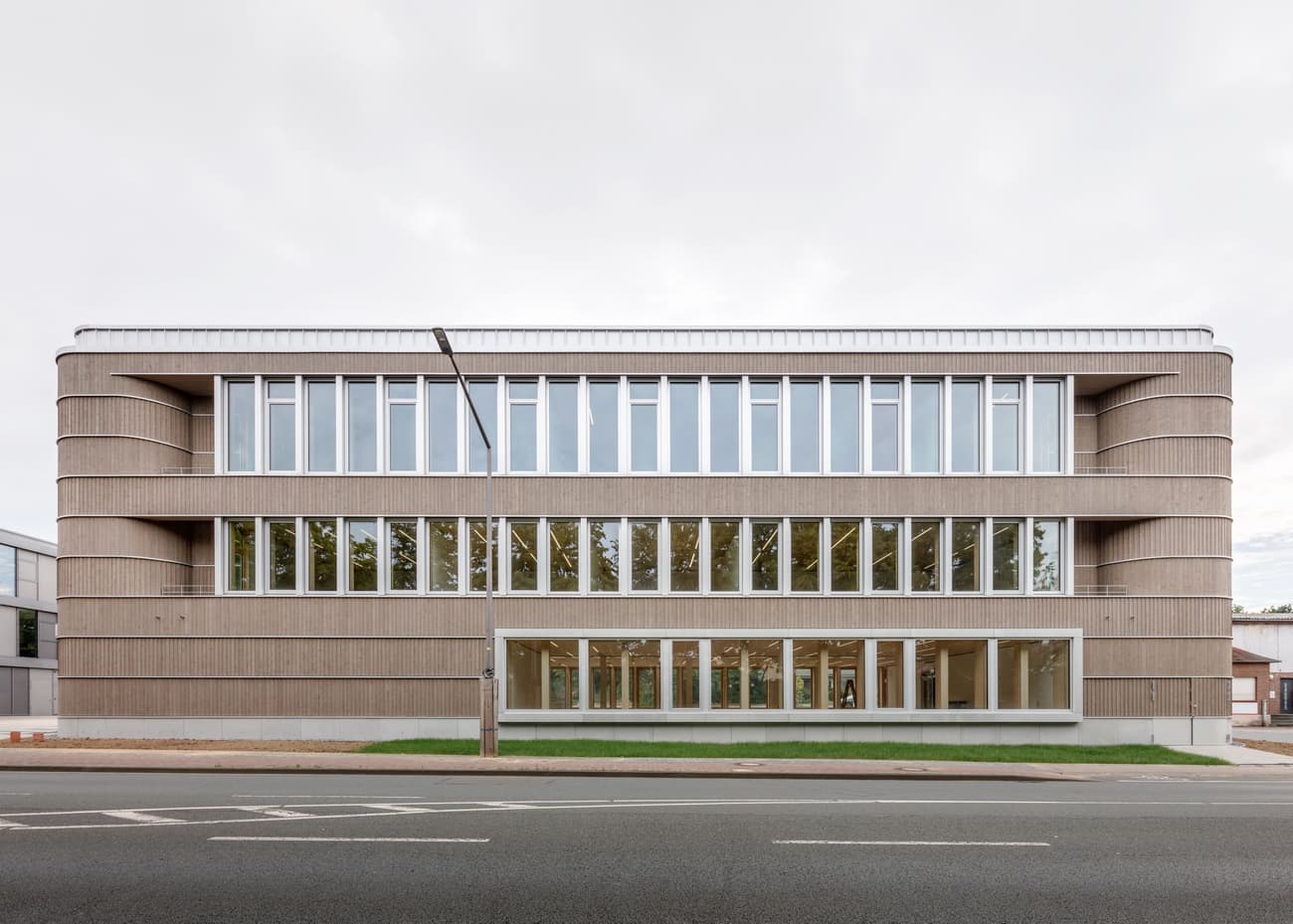 Architectural project - beige facade, commercial facade, modern workspace, horizontal lines, symmetrical design, modernist design, rectilinear form, modern office, office building, structural clarity, sleek facade, rooftop, symmetrical facade, corporate design, urban workspace, professional environment, business center, horizontal panels, minimal design, natural materials, wood, timber, urban setting, natural light, sustainable design, glass, eco design, contemporary architecture, grey, neutral tones, daylight, urban development, city architecture, concrete, flat roof, minimalist style, passive house, modern facade, clean lines, large windows, window wall, timber cladding, wood cladding, white, energy efficient, concrete base, glass windows, modern style, urban architecture, simple lines, light facade, public building, glass facade, rectangular form, urban facade, street view, contemporary building