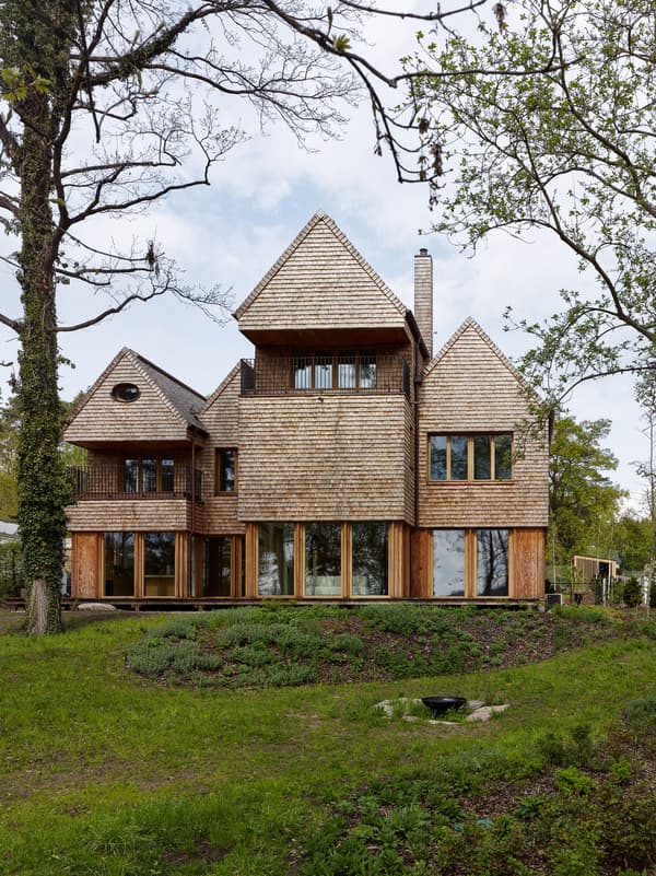Architectural project - wood, timber, raw materials, natural light, outdoor living, glass, warm tones, timber structure, green, beige, brown, exterior design, Scandinavian influence, natural setting, rural architecture, organic design, rustic charm, glass doors, natural landscape, biophilic design, passive house, large windows, wood cladding, cozy vibe, wood house, timber house, energy efficient, earthy tones, pitched roof, rustic architecture, greenery, garden view, woodland retreat, shingle roof, nature integration, wooden facade, wooden panels, eco house, rustic home, forest home, cabin style, wooden cladding, steep roof, countryside house, sustainable house, residential house, family home, multistory house, inviting exterior, custom build, unique architecture