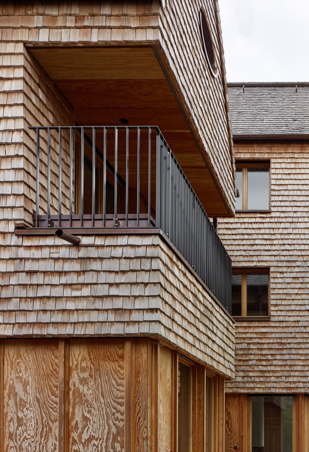 Architectural project - natural materials, architectural detail, wood, timber, grey, natural light, warm tones, eco design, sustainable construction, beige, brown, wood facade, timber facade, daylight optimization, rustic modern, weathered wood, neutral palette, natural finish, durable materials, green architecture, circular design, modern rustic, biophilic design, passive house, inviting home, energy efficient, earthy tones, natural texture, artisanal design, cozy exterior, wooden house, wooden cladding, shingle siding, rustic exterior, residential building, modern home, contemporary house, balcony design, outdoor balcony, black railing, simple railing, wooden texture, sustainable facade, exterior wood, outdoor design, textured facade, craftsmanship, energy saving, warm exterior, honey tones