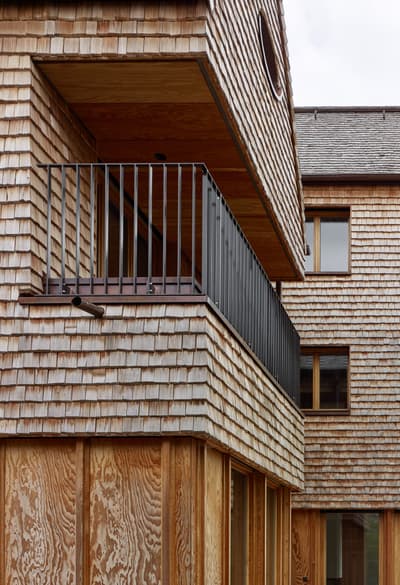 Architectural project - natural materials, architectural detail, wood, timber, grey, natural light, warm tones, eco design, sustainable construction, beige, brown, wood facade, timber facade, daylight optimization, rustic modern, weathered wood, neutral palette, natural finish, durable materials, green architecture, circular design, modern rustic, biophilic design, passive house, inviting home, energy efficient, earthy tones, natural texture, artisanal design, cozy exterior, wooden house, wooden cladding, shingle siding, rustic exterior, residential building, modern home, contemporary house, balcony design, outdoor balcony, black railing, simple railing, wooden texture, sustainable facade, exterior wood, outdoor design, textured facade, craftsmanship, energy saving, warm exterior, honey tones