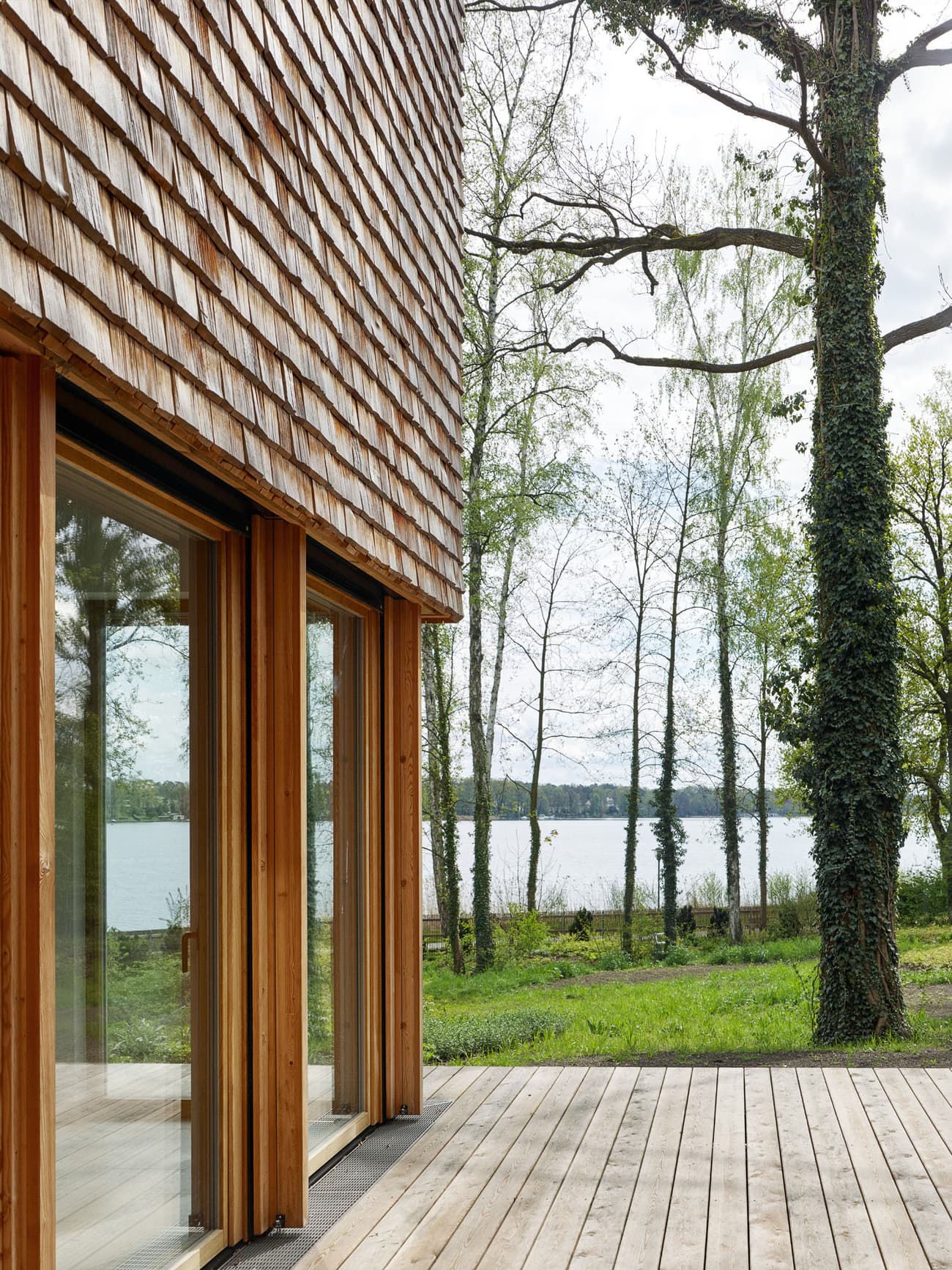 Architectural project - natural materials, wood, timber, grey, natural light, passive design, glass, warm tones, daylight, beige, brown, wood facade, timber facade, eco friendly, natural setting, simple design, Scandinavian style, serene space, natural palette, biophilic design, eco home, indoor outdoor, timber cladding, timber house, Nordic style, large window, landscape view, energy efficient, rustic style, open plan, inviting space, earthy tones, cozy atmosphere, nature retreat, forest view, timber deck, peaceful vibe, sustainable cabin, nature integration, green design, rustic retreat, lakeside view, wooden house, shingle, wooden cladding, shingle siding, shingle facade, wood siding, waterfront view, lake cabin, eco retreat, outdoor deck, wooden deck, glass door, floor to ceiling glass, wooden textures, rustic textures