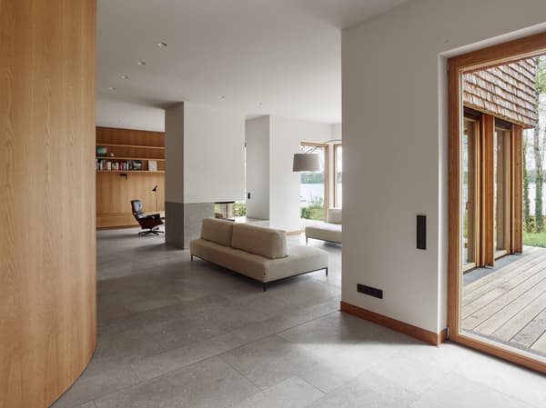 Architectural project - natural materials, tranquil space, wood, timber, grey, natural light, glass, modular design, eco design, neutral tones, daylight, timber facade, light wood, minimalist style, glass doors, timber panels, sustainable home, passive house, contemporary home, large windows, indoor outdoor, white, cozy vibe, inviting home, Nordic style, landscape view, energy efficient, earthy materials, stone, relaxed living, open layout, open plan, minimalist decor, warm atmosphere, residential design, modern living room, spacious interior, Scandinavian design, stone flooring, reading nook, modern fireplace, seating area, lounge chairs, built-in shelves, wall shelf, wood trim, lake view, comfortable seating, family living, spacious home