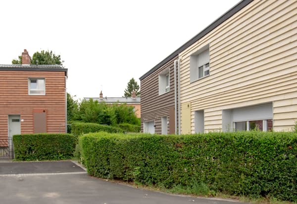Architectural project - beige facade, exterior facade, cladding, horizontal lines, driveway, community living, row houses, townhouses, residential cluster, suburban housing, neat facade, brown facade, green hedges, manicured hedges, landscaped front, modern neighborhood, housing development, suburban style, compact houses, family homes, daylight capture, minimal design, natural materials, eco-friendly design, wood, timber, outdoor space, natural light, passive design, contemporary style, green, neutral tones, beige, brown, concrete, green architecture, modern facade, clean lines, white facade, timber cladding, wood cladding, white, energy efficient, brick, functional layout, modern living, residential area, simple architecture, linear facade, sustainable living, urban living