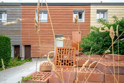 Architectural project - grass, vibrant color, horizontal lines, plants, terracotta blocks, residential landscape, natural materials, sustainable materials, timber, outdoor space, sustainable design, recycled materials, warm tones, modular design, contemporary style, beige, brown, low carbon design, eco friendly, facade detail, orange, circular construction, earth tones, biophilic design, passive house, modern facade, timber cladding, exterior texture, brick, brick facade, greenery, garden view, earthy palette, inviting exterior, residential building, textured facade, warm exterior, facade rhythm, urban garden, townhouse, urban living, urban housing, modern residential