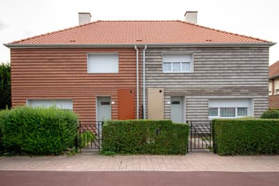 Architectural project - facade, duplex, side by side, stone cladding, gray, brickwork, symmetrical design, terracotta roof, two-tone facade, community living, lawn, pathway, privacy hedge, double doors, residential suburb, natural materials, sustainable materials, wood, warm tones, eco design, contemporary style, neutral tones, beige, brown, concrete, functional design, simple design, minimalist design, neutral colors, exterior, modern facade, clean lines, stone, clay, warm colors, terracotta, brick, brick facade, integrated design, wooden cladding, family home, residential building, light facade, green landscaping, modern suburb, architectural rhythm, energy efficiency, clay tiles, suburban house, urban living, urban housing, entryway