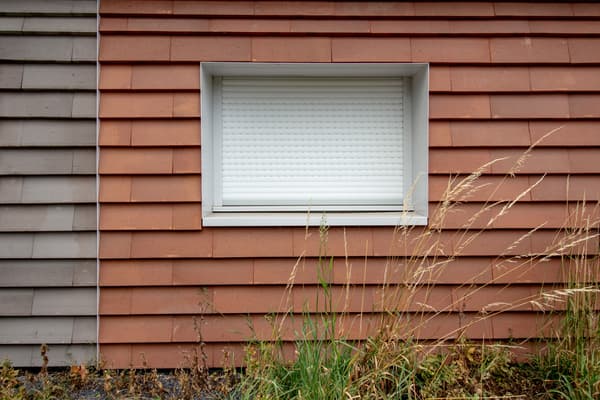 Architectural project - weathered look, residential exterior, tiled facade, red tiles, rural aesthetic, traditional vibe, earthen tones, terracotta facade, terracotta cladding, red cladding, white window, shuttered window, layered texture, minimalist window, simple window, natural materials, architectural detail, sustainable materials, warm tones, exterior design, exterior wall, functional design, farmhouse style, exterior detail, natural textures, durable materials, modern rustic, clean lines, white, textured wall, plaster, structural element, terracotta, rustic exterior, sustainable facade, contemporary facade, facade design, modern exterior, window detail, building envelope, eco facade, red