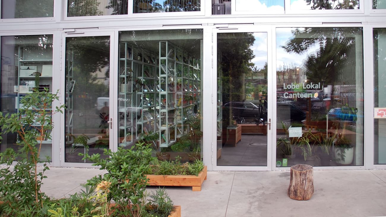 Architectural project - urban greenery, silver, metal frames, natural integration, transparency, polished concrete floor, outdoor plants, natural materials, eco-friendly design, raw materials, metal, relaxed vibe, natural light, sustainable design, glass, community space, grey, neutral tones, city architecture, gathering space, concrete, architectural facade, industrial style, modern design, contemporary design, outdoor seating, modern facade, clean lines, large windows, inviting entrance, casual dining, sleek design, glass door, seamless transition, open space, urban garden, glass facade, glass wall, indoor plants, eco facade, street view, urban style