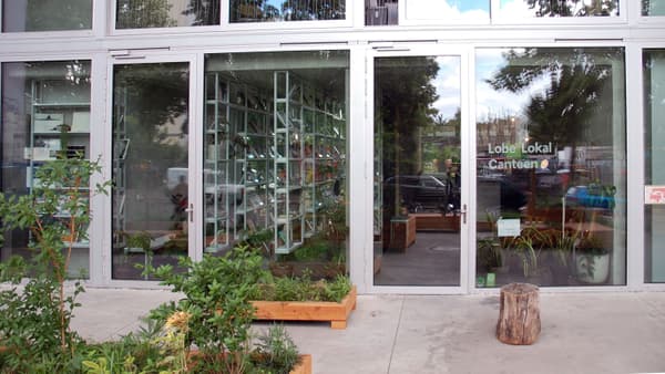 Architectural project - urban greenery, silver, metal frames, natural integration, transparency, polished concrete floor, outdoor plants, natural materials, eco-friendly design, raw materials, metal, relaxed vibe, natural light, sustainable design, glass, community space, grey, neutral tones, city architecture, gathering space, concrete, architectural facade, industrial style, modern design, contemporary design, outdoor seating, modern facade, clean lines, large windows, inviting entrance, casual dining, sleek design, glass door, seamless transition, open space, urban garden, glass facade, glass wall, indoor plants, eco facade, street view, urban style