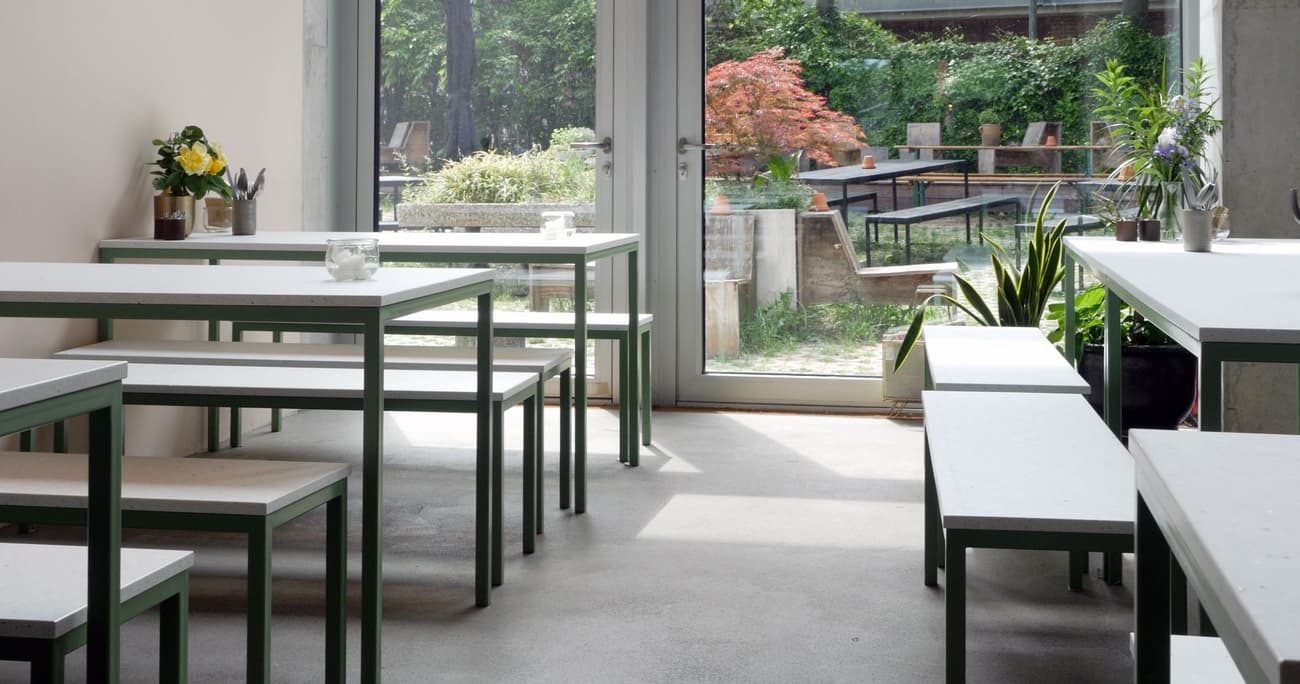 Architectural project - green accents, urban cafe, vibrant plants, fresh vibe, modern cafe, metal frame, metal, natural light, sustainable design, glass, contemporary style, grey, green, neutral tones, daylight, concrete, eco friendly, industrial touch, minimalist design, social space, public space, pastel green, light tones, large windows, indoor outdoor, white, open plan, inviting space, casual dining, cozy atmosphere, relaxed setting, outdoor connection, greenery, garden view, green design, bright interior, sliding doors, concrete floor, simple furniture, indoor plants