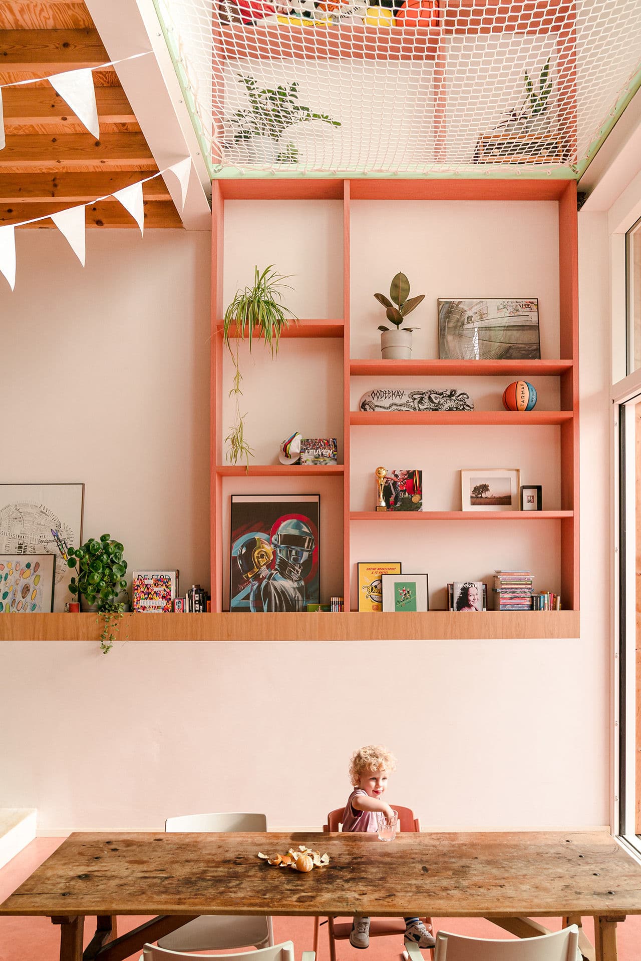 Architectural project - vibrant design, artistic vibe, playful interior, potted plants, homey vibe, bohemian touch, colorful decor, pastel pink, pink, wood, timber, relaxed vibe, natural light, eclectic style, warm tones, exposed beams, daylight, light wood, natural wood, casual seating, gallery wall, beige tones, cozy nook, timber ceiling, wooden table, inviting space, warm atmosphere, greenery, bright interior, nordic influence, family room, open shelving, spacious feel, Scandinavian inspiration, indoor plants, high ceiling