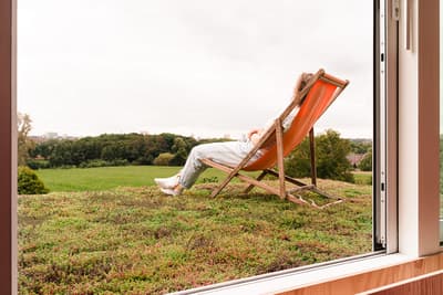 Architectural project - tranquil scene, peaceful environment, city escape, rooftop garden, indoor green, balcony view, wood details, folding chair, eco roof, timber, passive design, sustainable design, green, neutral tones, landscape architecture, beige, eco friendly, natural textures, relaxation, serene space, outdoor seating, orange, natural landscape, green architecture, earth tones, biophilic design, scenic view, indoor outdoor, white, large window, outdoor view, natural colors, panoramic view, environmental design, nature retreat, fresh air, seamless transition, urban nature, open window, green roof, living roof, picture window