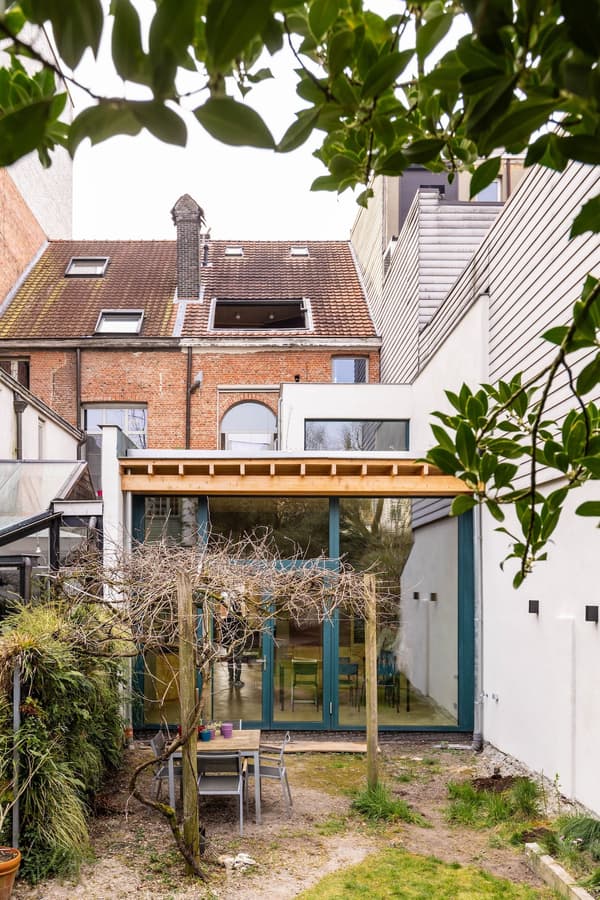 Architectural project - terrace, city garden, modern addition, contemporary extension, home extension, brick house, patio, row house, cozy garden, backyard design, urban backyard, brown roof, minimal design, wood, timber, natural light, glass, warm tones, eco design, contemporary style, green, neutral tones, exposed beams, daylight, brown, concrete, light wood, wooden beams, honey wood, natural textures, outdoor seating, sustainable home, timber roof, clean lines, white walls, indoor outdoor, white, open plan, glass walls, inviting space, alfresco dining, brick, relaxing space, brick facade, garden view, residential architecture, green design, family home, sliding doors, modern style, glass facade, urban home, mixed materials, urban retreat, city dwelling