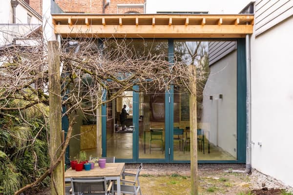 Architectural project - minimalist garden, green view, modern extension, patio, wooden pergola, backyard, residential extension, house extension, timber canopy, small patio, urban extension, outdoor table, outdoor chairs, maple wood, natural materials, timber, steel, outdoor space, natural light, glass, warm tones, contemporary style, green, daylight, beige, brown, light wood, multifunctional space, eco friendly, modern design, compact space, minimalist design, neutral colors, Scandinavian vibe, sustainable building, earth tones, stone, open plan, garden dining, cozy atmosphere, nature connection, bright interior, family home, sliding doors, urban garden, glass facade, indoor outdoor flow