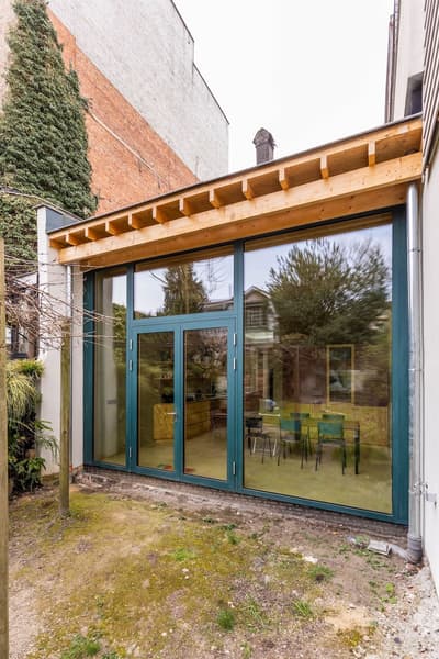 Architectural project - home extension, modern extension, small garden, city home, expansion, garden facade, patio doors, backyard view, building addition, tall windows, wood, timber, timber frame, natural light, sustainable design, glass, grey, green, neutral tones, exposed beams, daylight, beige, concrete, light wood, eco friendly, Scandinavian influence, wooden beams, natural textures, contemporary design, minimalist design, glass doors, biophilic design, large windows, indoor outdoor, Nordic style, wood frame, energy efficient, open plan, family space, dining area, inviting space, brick, residential design, outdoor connection, exterior view, green design, seating area, bright interior, modern home, sliding doors, open space, cozy home, urban garden, glass facade, home renovation, urban living