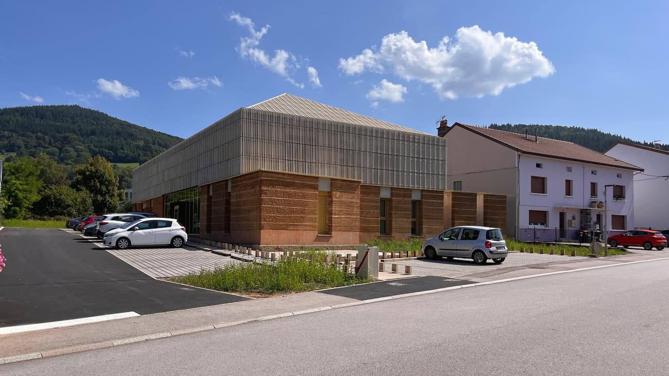 Architectural project - harmony with nature, natural integration, rustic materials, warm facade, mixed material, architectural layers, green spaces, rustic touch, sustainable design, beige, brown, modern aesthetic, daylight optimization, minimalist style, light brown, neutral palette, community center, timber detailing, eco-friendly materials, eco construction, rammed earth, biophilic design, natural ventilation, modern facade, clean lines, large windows, energy efficient, wood accents, earthy tones, outdoor connection, rural setting, landscape design, earthy textures, passive solar, innovative materials, public building, urban context, glass facade, building envelope, contrasting textures, geometric form, street view, contemporary building