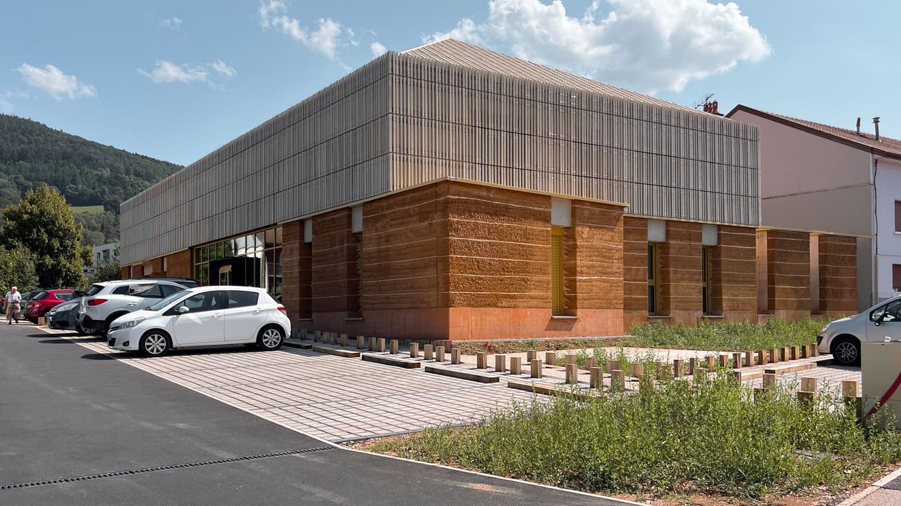 Architectural project - harmony with nature, natural integration, subtle design, earthy aesthetic, terracotta tones, cultural space, minimalist landscape, natural materials, sustainable design, beige, brown, light wood, eco friendly, honey wood, rustic modern, contemporary design, neutral palette, passive cooling, community center, timber panels, rammed earth, green architecture, natural ventilation, modern facade, wood cladding, simple elegance, earthy tones, warm colors, modern rural, modern exterior, public building, urban context, innovative architecture, architectural contrast, texture contrast