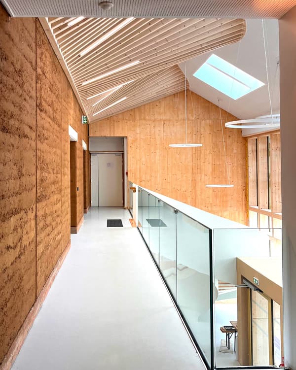 Architectural project - vertical elements, cozy hallway, residential corridor, transitional space, mezzanine, linear lighting, glass railing, acoustic design, ceiling slats, simple interior, warm interior, indoor space, natural materials, soft lighting, eco-friendly design, wood, timber, raw materials, natural light, sustainable design, warm tones, eco design, neutral tones, daylight, wooden ceiling, open area, beige, light wood, modern design, contemporary design, Scandinavian style, minimalist design, light tones, timber walls, rammed earth, green architecture, earth tones, passive house, clean lines, white, Nordic style, textured wall, energy efficient, plaster, timber ceiling, inviting space, wood texture, bright space, plaster walls, minimalistic, educational building, corridor, hallway, skylight, wooden walls