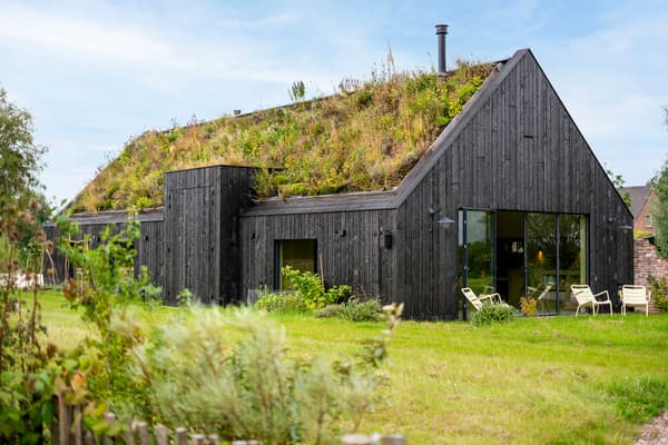 Architectural project - modern barn, sliding glass, garden chairs, garden setting, grass roof, black house, burnt wood, carbon neutral, serene vibe, wood, outdoor living, reclaimed materials, recycled materials, glass, eco design, sustainable architecture, green, wood facade, eco friendly, farmhouse style, rustic modern, rustic charm, Scandinavian style, minimalist design, black, outdoor seating, natural landscape, biophilic design, sustainable home, passive house, large windows, indoor outdoor, timber cladding, countryside home, energy efficient, nature-inspired, quiet retreat, secluded retreat, nature integration, green design, nordic influence, modern rural, natural insulation, environmentally conscious, green roof, living roof, low impact design, rural house, dark facade, charred timber