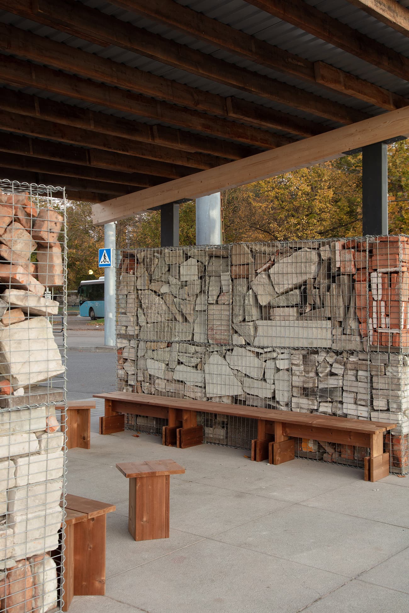 Architectural project - urban furniture, outdoor furniture, timber benches, public seating, gabion wall, recycled seating, gabion design, wood benches, autumn setting, cost-effective design, budget-friendly, natural materials, architectural detail, wood, timber, steel, metal, outdoor space, sustainable design, recycled materials, warm tones, modular design, exposed structure, community space, grey, neutral tones, urban environment, brown, industrial style, eco friendly, open structure, natural setting, simple design, casual seating, social space, public space, outdoor seating, urban design, raw texture, modern rustic, stone, earthy tones, stone wall, wooden seating, green design, rustic aesthetic, urban context, stone texture