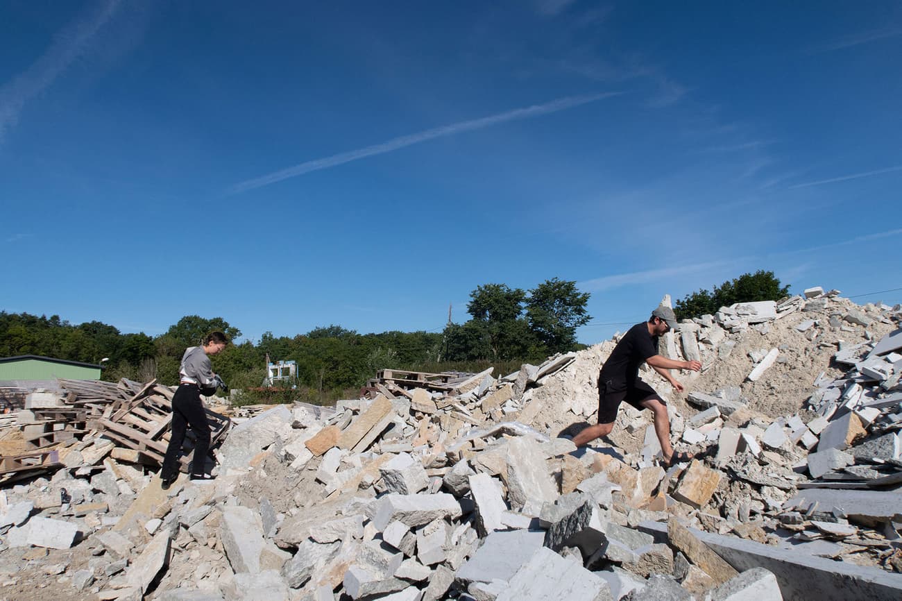 Architectural project - renovation process, outdoor work, sustainable practice, manual labor, green construction, circular economy, repurposed materials, environmental impact, rubble pile, construction debris, demolition site, recycling material, reuse construction, eco-friendly demolition, sustainable site, renovation site, builders at work, rubble heap, rock pile, stone fragments, stone reuse, stone recycling, landscape work, debris handling, eco-conscious construction, building waste, rubble recycling, rubble clearing, worker action, construction practice, outdoor scene, sustainable building practices, infrastructure, raw materials, outdoor space, eco design, construction site, building site, concrete, natural setting, blue sky, natural landscape, circular design, stone, gravel