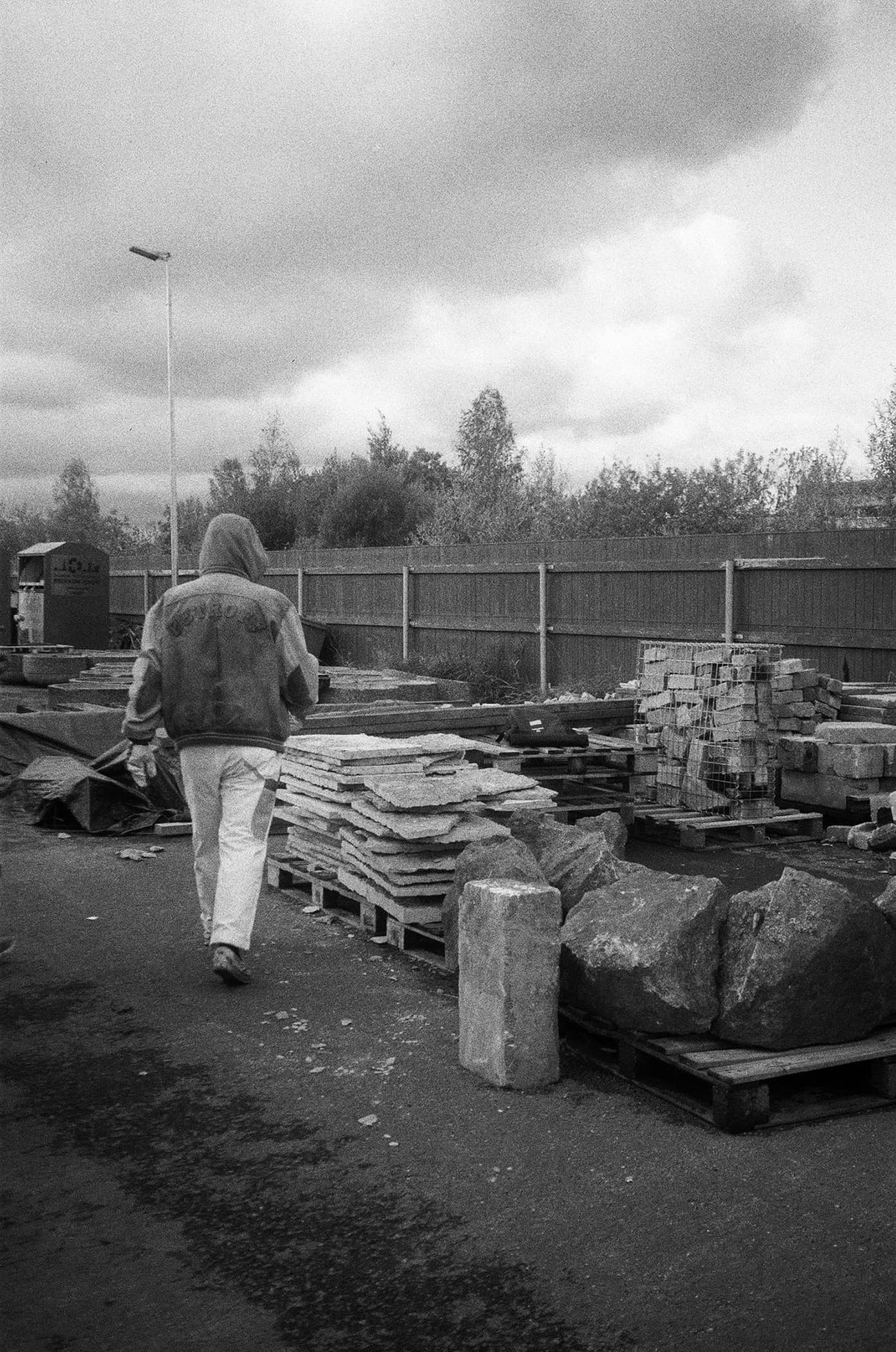 Architectural project - outdoor workspace, outdoor storage, construction supplies, paving stones, urban texture, construction zone, stone slabs, stacked stones, monochrome aesthetics, worker presence, stone storage, utility space, palette stacking, industrial atmosphere, organized materials, industrial layout, stone surface, supply area, architecture planning, material texture, industrial zone, grey tones, urban setting, raw materials, outdoor area, grey, site work, urban environment, industrial vibe, construction materials, building site, concrete, black, industrial site, rustic texture, stone, rough texture, heavy materials, black and white
