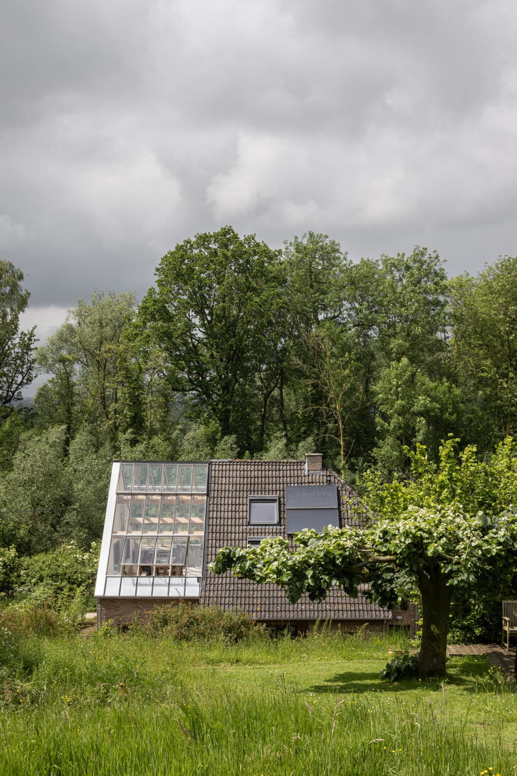 Architectural project - natural elements, integration with nature, tiled roof, triangular window, rural, garden, serene, peaceful, compact, efficiency, retreat, haven, leisure, grey roof, white frame, blending with nature, low carbon materials, minimalist, architectural design, timber, outdoor space, natural light, rustic touch, passive design, glass, grey, green, concrete, modern aesthetic, daylight optimization, eco friendly, contemporary, simple design, relaxation, exterior, tranquil setting, modern, sustainable home, nature view, clean lines, large windows, white, landscape view, energy efficient, sloped roof, forest view, countryside, house, greenery, countryside living, natural habitat, eco house, low impact, biodiversity, green surroundings, residential, home, dark tiles, glass facade, innovative architecture, glass wall, connection to nature, modern cabin, skylight, private dwelling