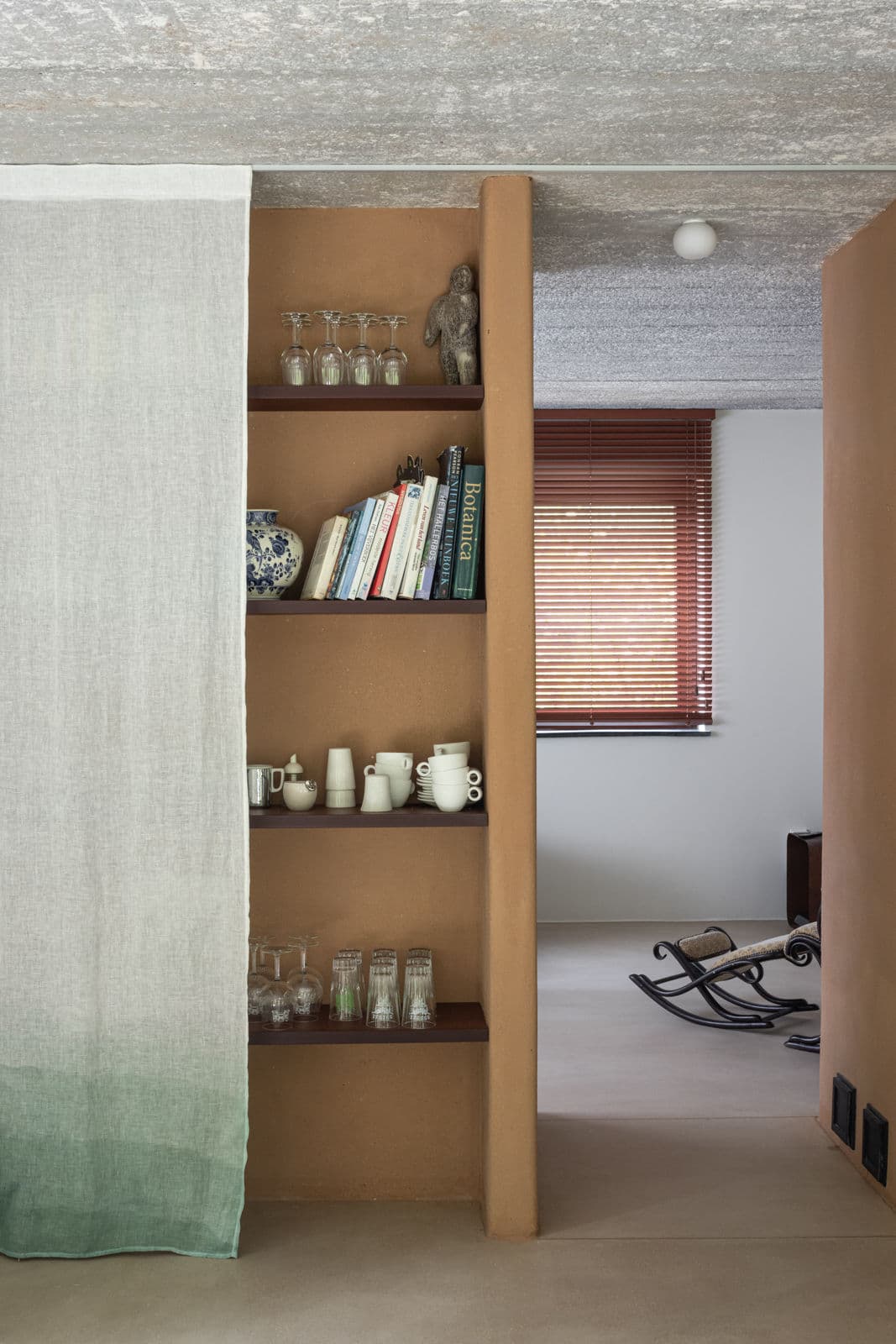 Architectural project - rustic interior, earthy style, earth tone, clay color, timber shelf, wood shelf, built-in shelf, cottage vibe, homely feel, muted colors, vintage style, Scandinavian touch, hygge, boho decor, low carbon interior, private corner, functional decor, comfort living, intimate space, natural materials, wood, timber, natural light, sustainable design, warm tones, daylight, beige, brown, light wood, eco friendly, simple design, rustic charm, minimalist style, wooden floor, neutral palette, playful elements, soft hues, inviting home, textured wall, plaster wall, plaster, casual living, minimalist decor, warm atmosphere, clay, reading nook, cozy home, relaxed space, open shelving
