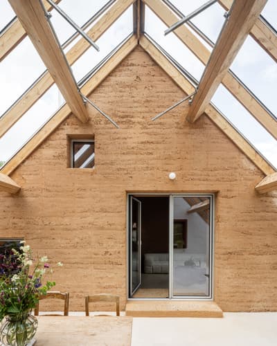 Architectural project - skylights, cottage vibe, Scandinavian touch, earth walls, earthen facade, minimalist furniture, farmhouse feel, comfort, cozy interior, warm interior, natural materials, sustainable materials, wood, timber, raw materials, relaxed vibe, natural light, sustainable design, glass, warm tones, eco design, sustainable architecture, exposed beams, daylight, beige, multifunctional space, rustic modern, light brown, neutral palette, glass doors, rammed earth, green architecture, modern rustic, biophilic design, passive house, timber roof, indoor outdoor, eco friendly home, textured wall, energy efficient, open plan, inviting space, earthy tones, wood roof, nature retreat, compact living, sliding doors, nordic influence, seamless transition, open space, airy atmosphere, simple furniture, rural retreat, casual elegance, vaulted ceiling