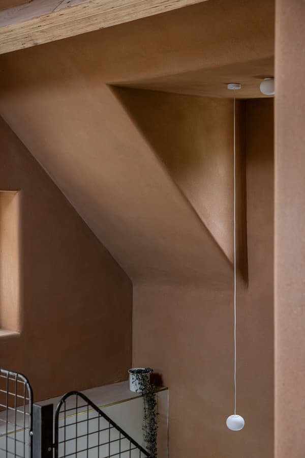 Architectural project - rustic interior, earth wall, geometric elements, sculptural design, white pendant, ceiling light, natural lighting, recessed window, architectural focus, wall niche, mindful living, materiality, earthen architecture, warm interior, natural materials, architectural detail, sustainable materials, shadow play, warm tones, eco design, sustainable architecture, neutral tones, daylight, intimate corner, rustic charm, contemporary design, minimalist design, natural finish, rammed earth, modern rustic, architectural simplicity, simple elegance, cozy vibe, textured wall, plaster wall, inviting space, earthy tones, minimalist aesthetic, pendant light, smooth surfaces, soft light, organic textures